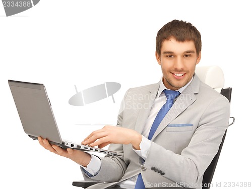 Image of young businessman sitting in chair with laptop