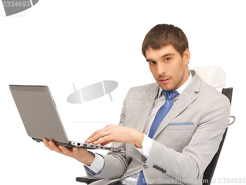Image of young businessman sitting in chair with laptop