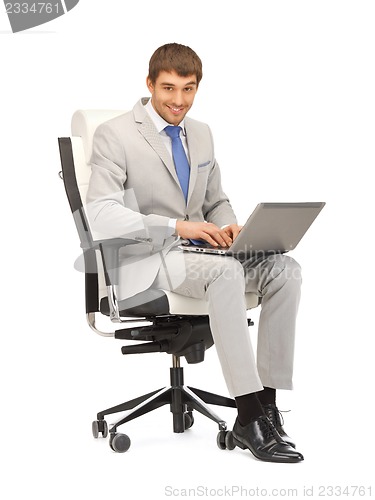 Image of young businessman sitting in chair with laptop