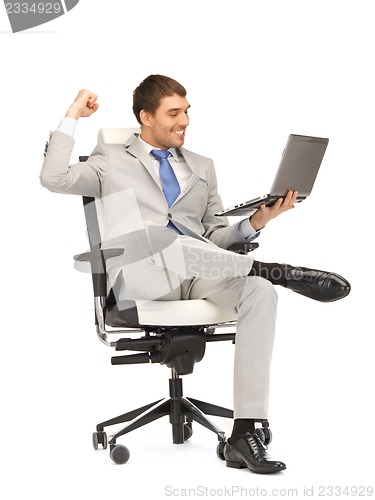 Image of young businessman sitting in chair with laptop