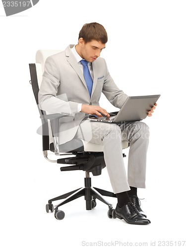 Image of young businessman sitting in chair with laptop