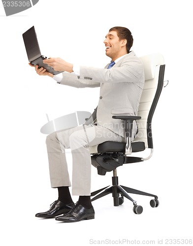 Image of young businessman sitting in chair with laptop