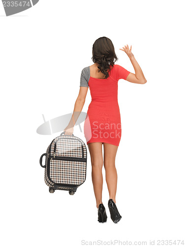 Image of woman with suitcase waving hand