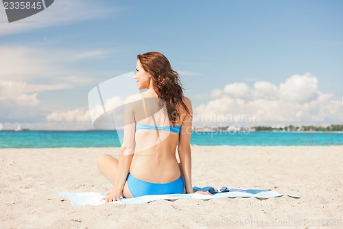 Image of happy smiling woman sitting on a towel