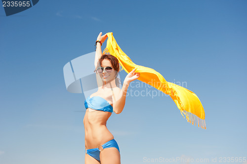 Image of happy woman with yellow sarong on the beach