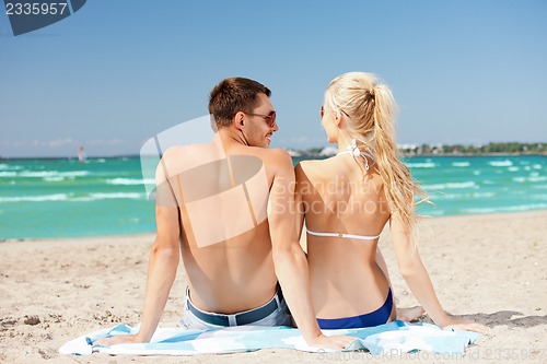 Image of happy couple sitting on the beach