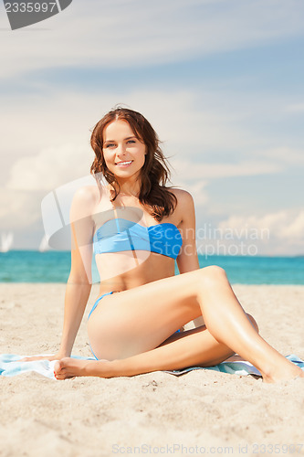 Image of happy smiling woman sitting on a towel