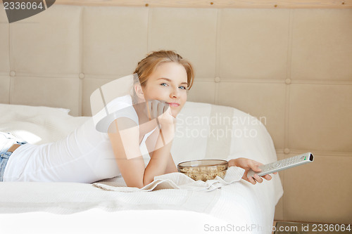 Image of happy teenage girl with TV remote and popcorn