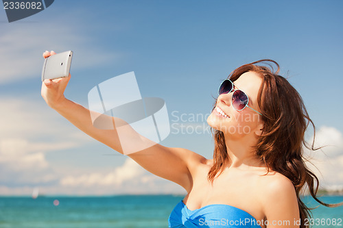 Image of happy woman with phone on the beach
