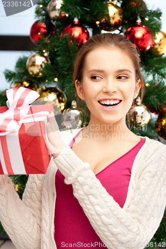 Image of happy woman with gift box and christmas tree
