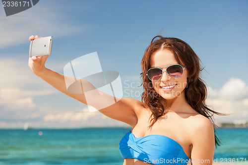 Image of happy woman with phone on the beach