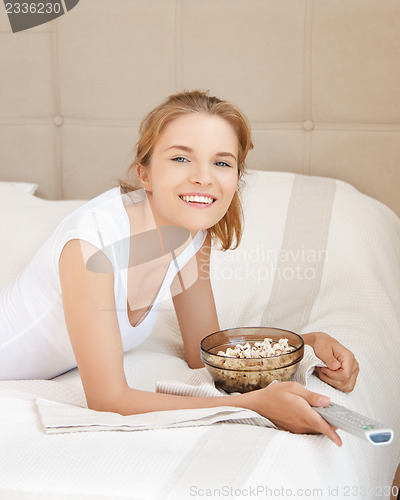 Image of happy teenage girl with TV remote and popcorn