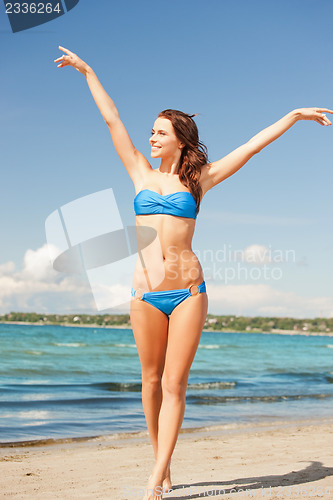 Image of happy smiling woman walking on the beach