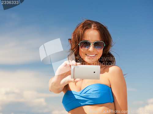 Image of happy woman with phone on the beach