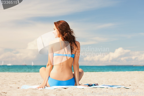 Image of happy smiling woman sitting on a towel