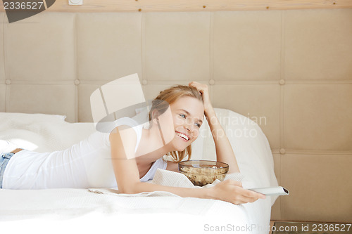 Image of happy teenage girl with TV remote and popcorn