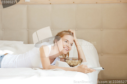 Image of happy teenage girl with TV remote and popcorn