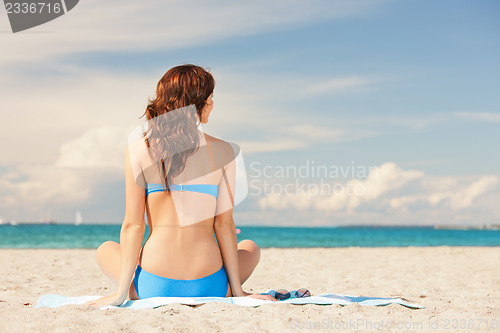 Image of woman practicing yoga lotus pose on the beach