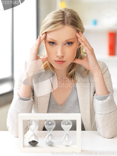Image of pensive businesswoman with sand glass