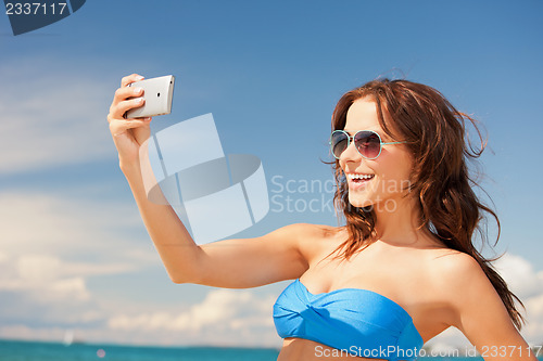 Image of happy woman with phone on the beach