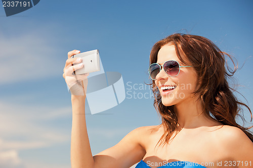 Image of happy woman with phone on the beach