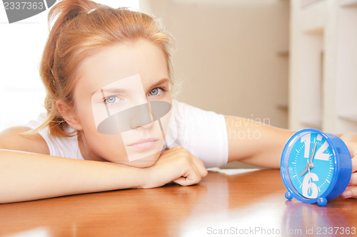 Image of pensive teenage girl with clock