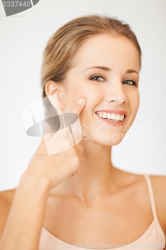 Image of beautiful woman pointing to cheek
