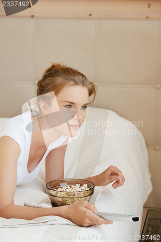 Image of happy teenage girl with TV remote and popcorn