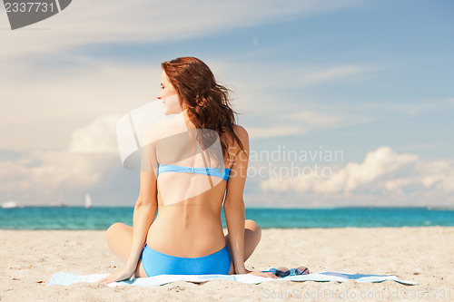 Image of happy smiling woman sitting on a towel