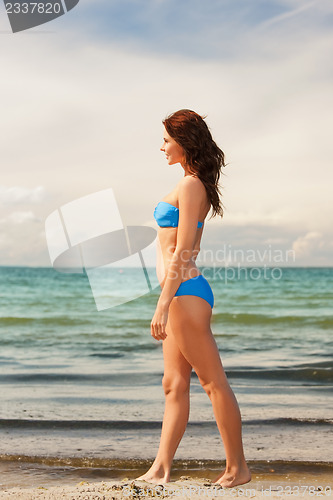 Image of happy smiling woman walking on the beach