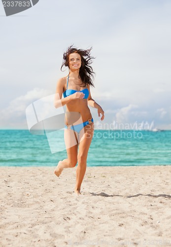 Image of happy smiling woman jogging on the beach