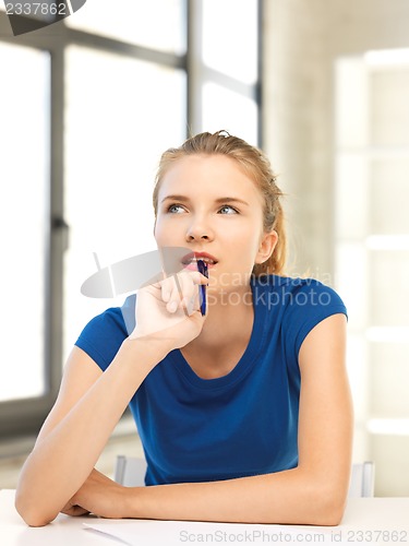 Image of pensive teenage girl with pen and paper