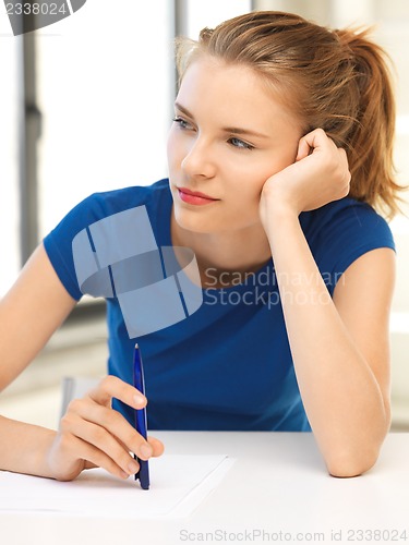 Image of pensive teenage girl with pen and paper