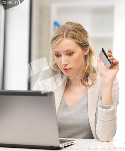 Image of serious woman with laptop computer and credit card