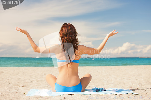 Image of woman practicing yoga lotus pose on the beach