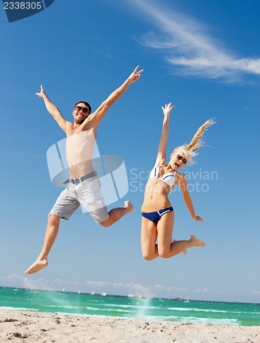 Image of happy couple jumping on the beach
