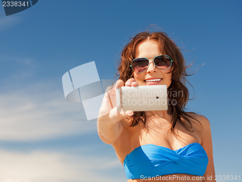 Image of happy woman with phone on the beach