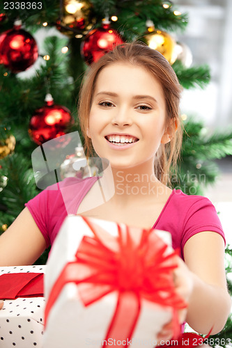 Image of happy woman with gift box and christmas tree