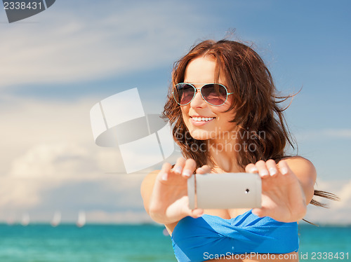 Image of happy woman with phone on the beach