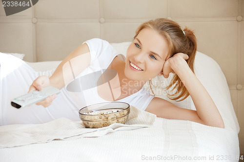 Image of happy teenage girl with TV remote and popcorn