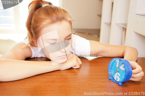 Image of pensive teenage girl with clock