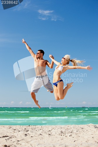Image of happy couple jumping on the beach
