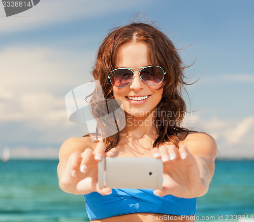 Image of happy woman with phone on the beach