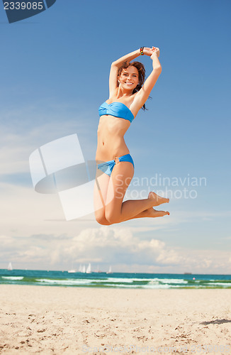 Image of happy jumping woman on the beach