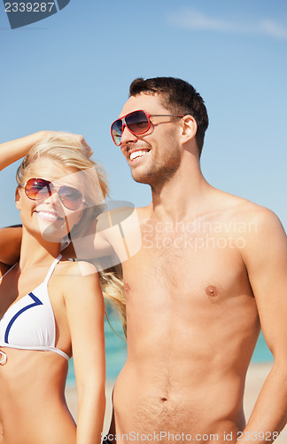 Image of happy couple in sunglasses on the beach