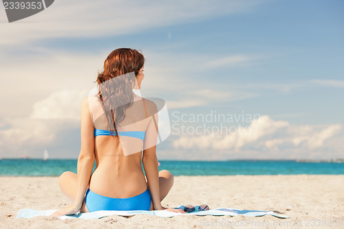 Image of woman practicing yoga lotus pose on the beach