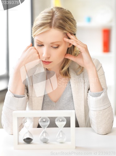 Image of pensive businesswoman with sand glass