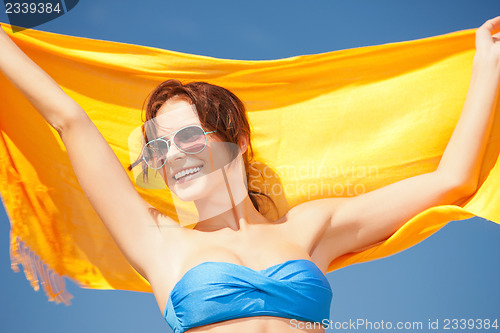 Image of happy woman with yellow sarong on the beach