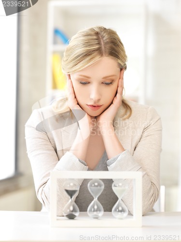 Image of pensive businesswoman with sand glass