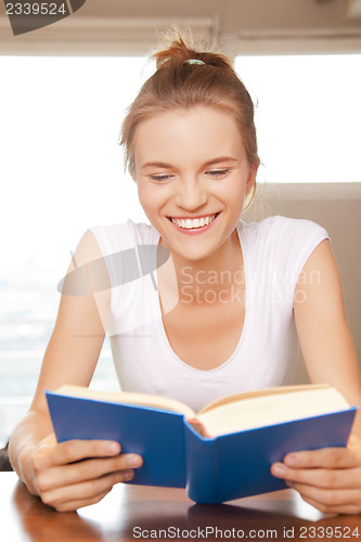Image of happy and smiling teenage girl with book